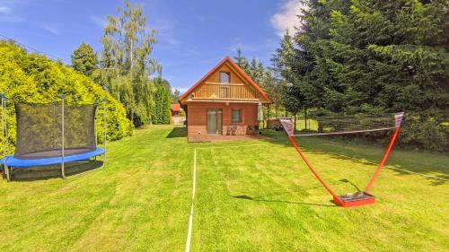 a large yard with a house and a swing at Chata Wilka - całoroczny dom z bali na wyłączność z 3 sypialniami in Brzegi Dolne