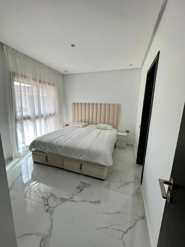 um quarto com uma cama num piso de mármore em Appartement Prestigia 3 chambres em Marraquexe