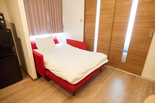 - un petit lit dans une chambre avec une chaise rouge dans l'établissement SG Premium KASAI - Vacation STAY 44353v, à Tokyo