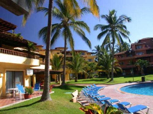a resort with chairs and a swimming pool and palm trees at Los Tules Ocean Front Studio 901 - 2nd floor in Puerto Vallarta