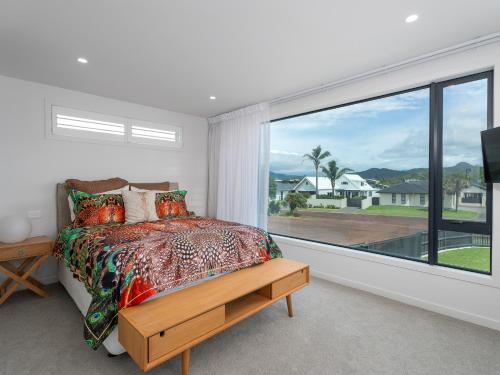a bedroom with a bed and a large window at Villa Viti - Pauanui Holiday Home in Pauanui