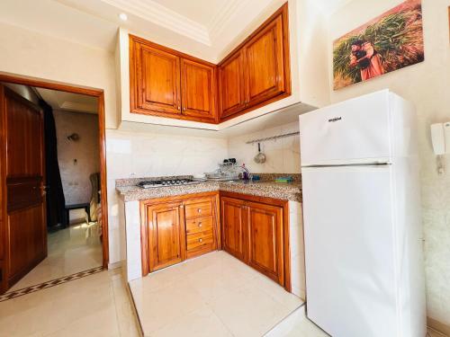 a kitchen with wooden cabinets and a white refrigerator at SABOR FAMILY APARTS -Jaouharat Al Atlas in Marrakech