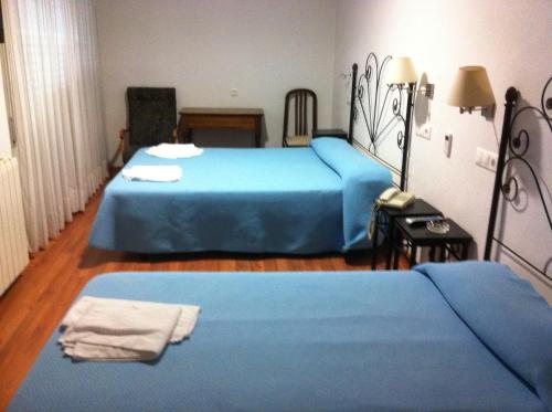 a bedroom with two beds with blue sheets at Hotel Mesón del Moro in Abarán