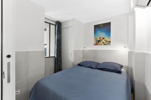 une chambre avec un lit avec des oreillers bleus dans l'établissement Cannes NG - Appartement à 10 mn du Palais des Festivals, à Cannes