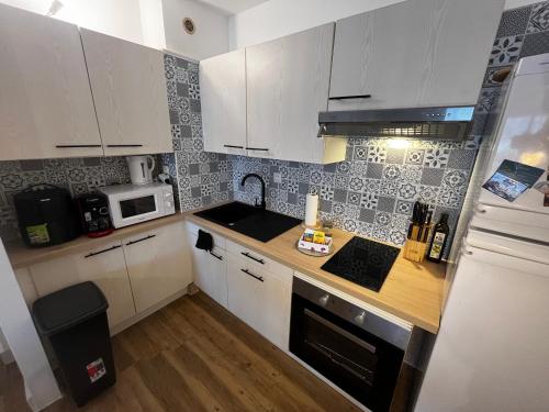 une cuisine avec des armoires blanches, un évier et un micro-ondes dans l'établissement Mediterranean sun beach, Palavas, à Palavas-les-Flots