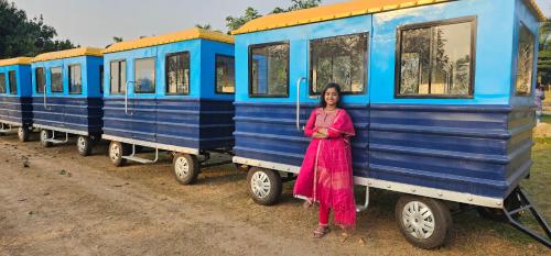 a woman standing in front of a blue train at MOTIJHIL,MURSHIDABAD in Murshidābād