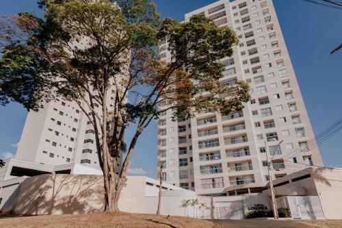 un arbre devant un grand bâtiment dans l'établissement Apartamentos de Temporada Araxá WIFI GRATUITO - ESPAÇO HOME OFFICE, à Araxá