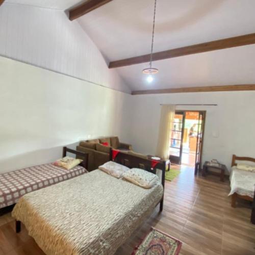 a bedroom with two beds and a living room at Estalagem Sitio Colibri in Cunha