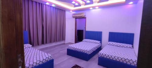 Zimmer mit 2 Betten und lila Vorhängen in der Unterkunft فندق الفخامة in El-Qaṭṭa