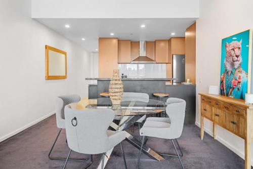 Un comedor con una mesa de cristal y sillas blancas. en 2-Bed, 500m From The Beach with Pool, Gym & Sauna, en Melbourne