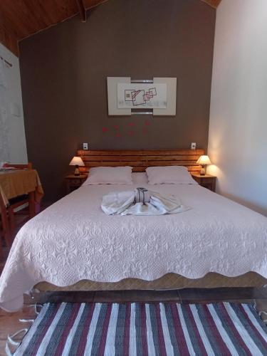 a bedroom with a bed with a white comforter at Recanto lavinia in Monte Verde