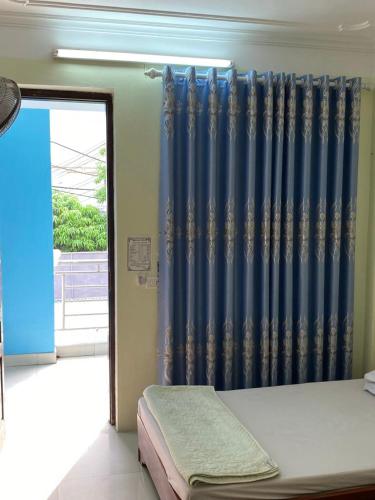 a bedroom with a blue curtain and a window at Khách Sạn Thục Quyên in Dong Quan