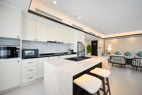 a kitchen with white cabinets and a counter with stools at Emerald Ho Tram Resort in Ho Tram