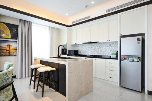 a kitchen with white cabinets and a counter with stools at Emerald Ho Tram Resort in Ho Tram