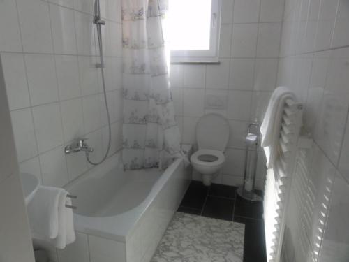 a white bathroom with a tub and a toilet at Hotel Mila in Reichenbach an der Fils