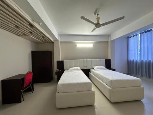 a bedroom with two beds and a ceiling fan at Hotel Kingfisher - Barishal in Barisāl