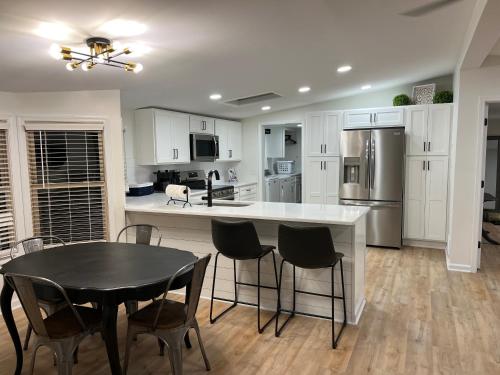 a kitchen with white cabinets and a black table and chairs at Whiskey Woods in Frankfort