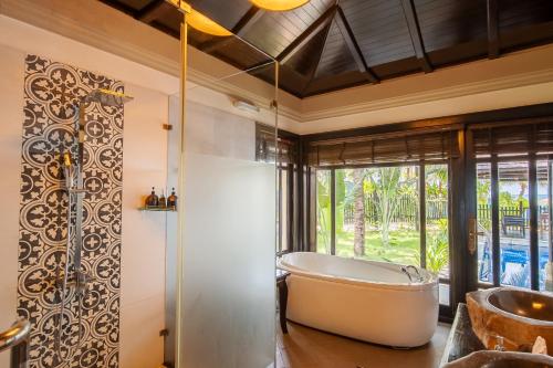 a bath tub in a bathroom with a window at Anja Beach Resort & Spa in Phu Quoc