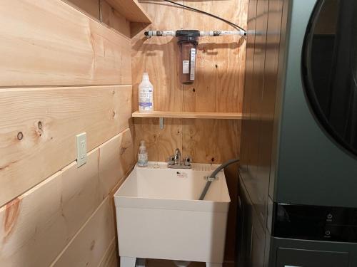 a bathroom with a white sink and wooden walls at Creekside Getaway - King Bed - Full Kitchen in Boone