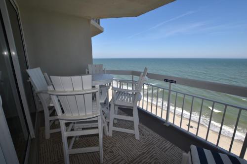 two chairs and a table on a balcony with the ocean at 0802 Waters Edge Resort condo in Myrtle Beach