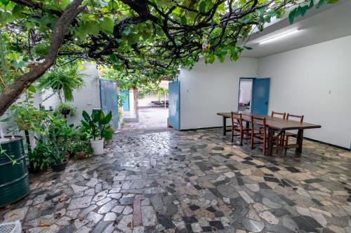 a room with a table and chairs and a tree at Quarto 05 Pousada Roosevelt in Uberlândia