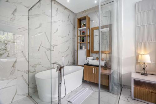 a bathroom with a tub and a glass shower at Villa Sun Lila by JB Villas in Seminyak