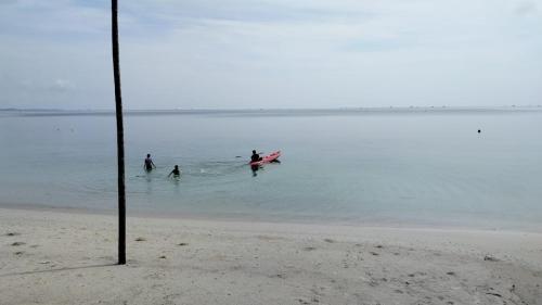 a group of people in the water at the beach at Madu Tiga Beach and Resort in Tanjung Pinang 