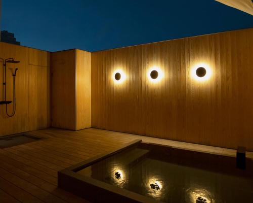 a bathroom with a tub with lights on the wall at 穴吹邸 / ANABUKI-TEI in Takamatsu