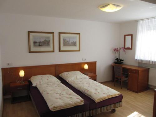 a bedroom with a bed and a desk with two lamps at Hotel Mila in Reichenbach an der Fils