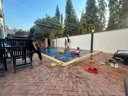a woman watching a child playing in a swimming pool at Maha Kali Hotel in Phumi Ta Phul