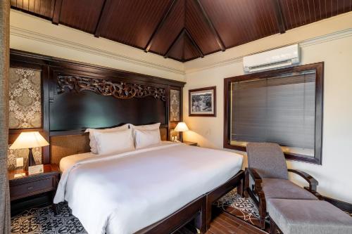 a bedroom with a large bed and a chair at Anja Beach Resort & Spa in Phu Quoc