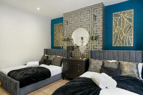 two beds in a bedroom with blue walls and a mirror at Platinum Grove B Modern Flat, 2 Beds with Free Parking in Kent