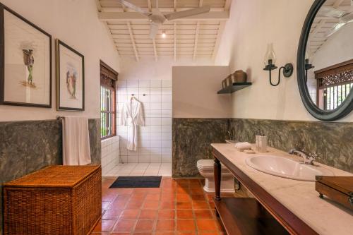 een badkamer met een wastafel, een toilet en een spiegel bij Uga Riva - Negombo in Negombo