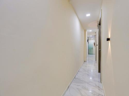 OYO HOTEL KING View في أحمد آباد: ممر به جدران بيضاء وأرضية بيضاء