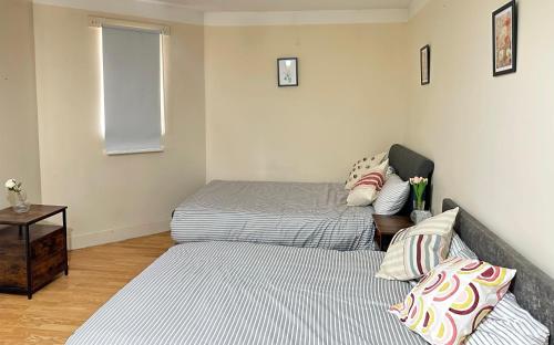 um quarto com 2 camas individuais e uma mesa em Wembley Stadium Serviced Apartment 2, 12mins to Central London em Londres