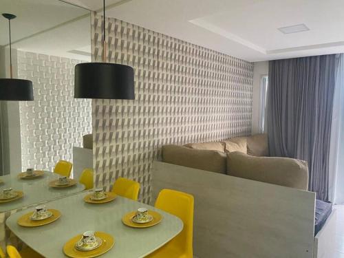 Flat completo em Muro Alto - Porto de Galinhas في إيبوجوكا: غرفة طعام مع طاولتين وكراسي صفراء