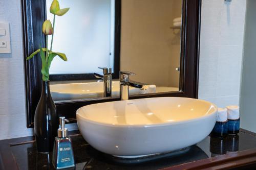 a bathroom with a white sink and a large mirror at Anja Beach Resort & Spa in Phu Quoc