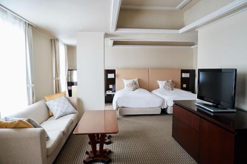 a living room with two beds and a couch at Hotel Crystal Palace in Hitachinaka