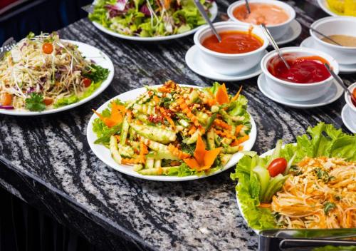 a table topped with plates of food and salads at Family Suite Hotel in Hanoi