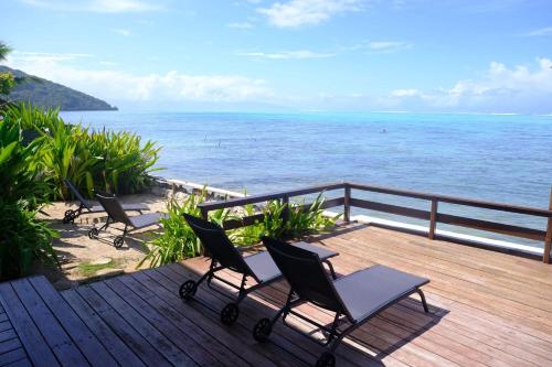 3 chaises assises sur une terrasse donnant sur l'océan dans l'établissement Maison d’hôtes bord de mer ia orana lodge, à Moorea