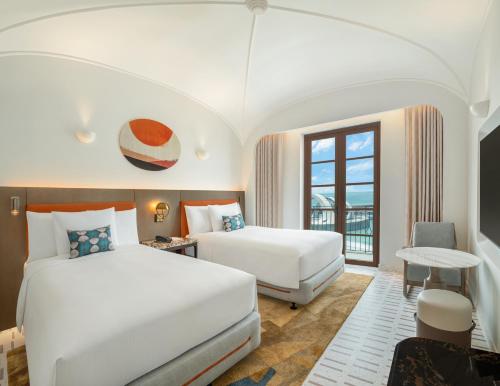 a hotel room with two beds and a window at La Festa Phu Quoc, Curio Collection By Hilton in Phu Quoc