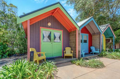 ナンブッカ・ヘッズにあるBIG4 Tasman Holiday Parks - Nambucca Headsのポーチに椅子が2脚置かれたカラフルな小屋