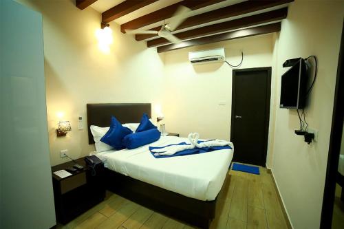 a bedroom with a bed with blue pillows and a television at SAPPHIRE INN in Puducherry