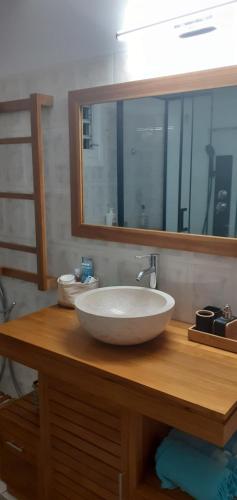 W łazience znajduje się biała umywalka i lustro. w obiekcie Le p'tit nid cocodydy w mieście Baillif