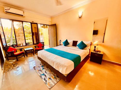 Hotel The Golden Shivam Resort - Big Swimming Pool Resort In Goa في Goa: غرفة نوم بسرير وطاولة وكراسي