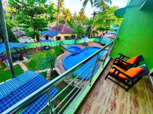 balcón con sillas y piscina en Hotel The Golden Shivam Resort - Big Swimming Pool Resort In Goa en Goa