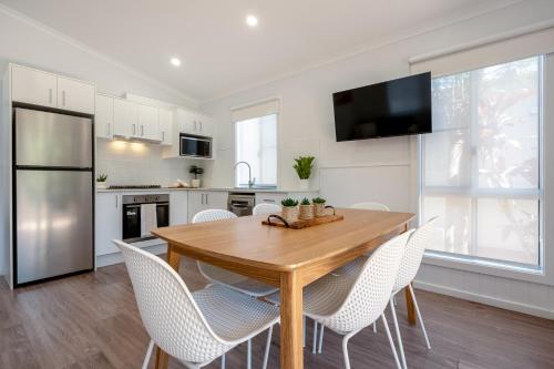 a kitchen with a wooden table and white chairs at BIG4 Tasman Holiday Parks - Nambucca Heads in Nambucca Heads
