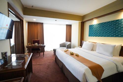 a hotel room with a large bed and a desk at Hotel Horison Ultima Bekasi in Bekasi