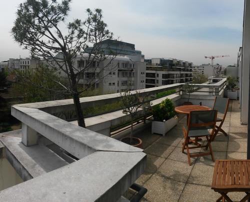 - un balcon avec une table et un arbre dans un bâtiment dans l'établissement Calm appartment with its terrace, à Levallois-Perret