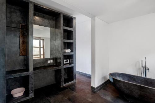 een badkamer met een zwart bad en een spiegel bij Villa Jepun by BaliSuperHost in Ubud